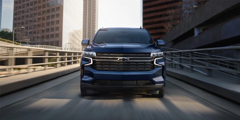 Image of a blue 2024 Chevrolet Tahoe in action, driving head-on toward the camera through a city